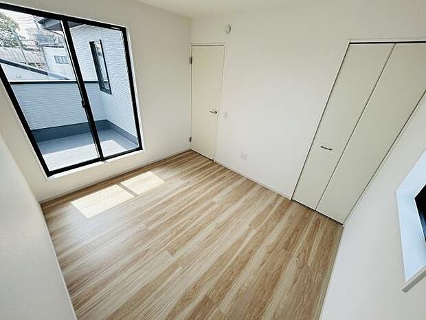 大きな窓から自然光がたっぷり差し込みます。シンプルな内装で家具の配置がしやすい洋室です。クローゼット付きで収納にも便利です。バルコニーへのアクセスも可能な設計です。清潔感のある空間が特徴的です。
