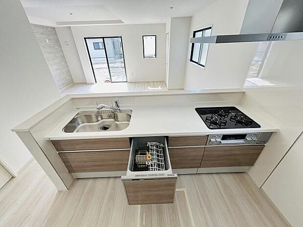 キッチンには広々としたカウンタースペースがあり調理の際に便利です。シンクとコンロが直線的に配置されており動線がスムーズです。食器洗浄機が備え付けられているため後片付けも簡単に行えます。