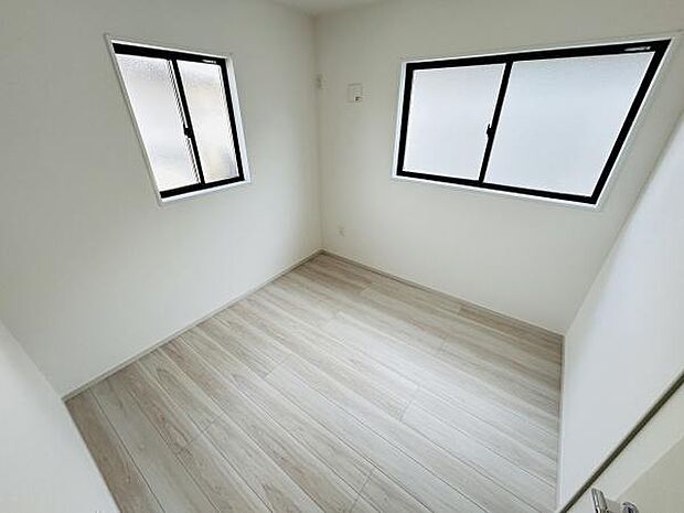 明るい木目調の床が印象的な洋室です。二面採光で室内がしっかりと照らされ快適な空間となっています。壁や天井も白で統一されているため清潔感も感じられます。家具の配置がしやすいシンプルな間取りです。