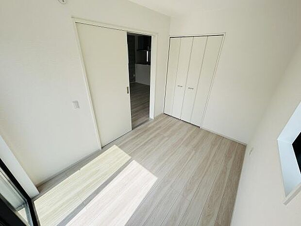 明るい色合いの床が印象的な洋室です。クローゼット収納が備わっており使い勝手の良い空間となっています。スライドドアで空間を有効活用できます。窓から自然光が差し込み日中も快適にお過ごしいただけます。