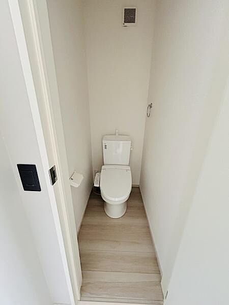 白を基調とした清潔感のあるトイレです。手入れがしやすいシンプルなデザインです。スリムな空間に配置されているため使い勝手も良好です。換気機能も備えられています。