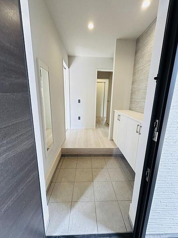 玄関スペースはすっきりとしたデザインで清潔感のある仕上がりです。大きな姿見が設置されており外出前のチェックに便利です。収納スペースも備わっており整理整頓がしやすい環境です。