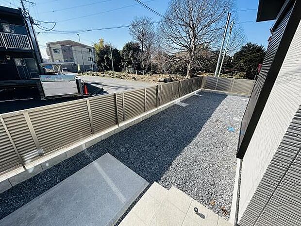 フェンスで囲まれたプライベートな庭が広がっています。シンプルな砂利敷きでメンテナンスがしやすい環境です。陽当たりも良好でゆったりとした空間を確保しています。