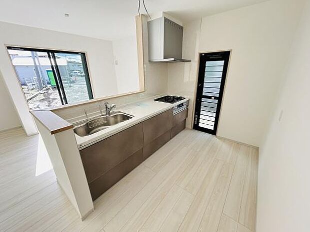 明るい陽射しが差し込むキッチンです。清潔感のある空間で作業もしやすそうです。横長のレイアウトがすっきりとしており動線も良好です。勝手口付きで通風も期待できます。