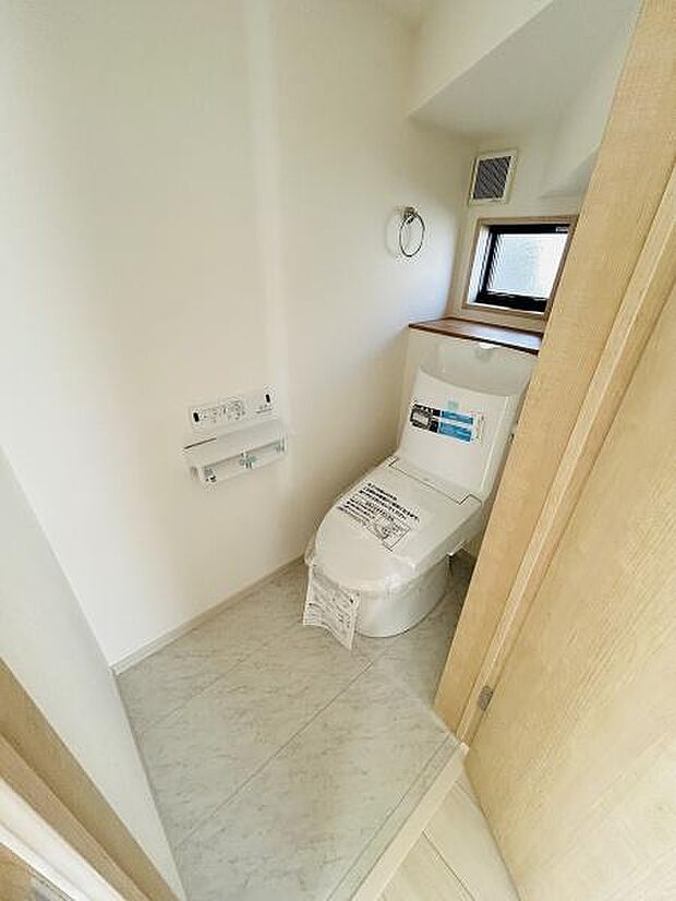窓付きで明るさが確保されたトイレです。壁に設置されたペーパーホルダーやスイッチ類も使いやすい配置です。清潔感のある内装でシンプルですっきりとした空間が魅力です。