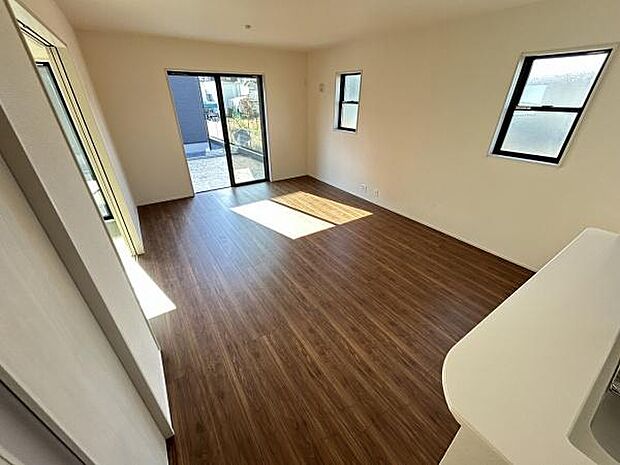 リビングの床は木目調仕上げで空間に落ち着いた雰囲気が広がっています。窓から自然光がしっかりと入ります。シンプルな内装が清潔感を感じさせます。出入り口も広く使いやすい設計です。