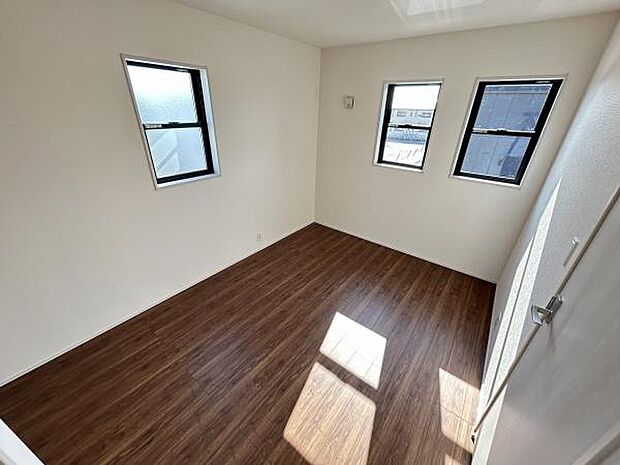 三つの窓から光がしっかり入る洋室です。床は落ち着いた色合いですっきりとした印象を与えます。壁や天井もシンプルで家具の配置がしやすい空間です。形が整っており色々な用途に活用しやすい洋室になっています。