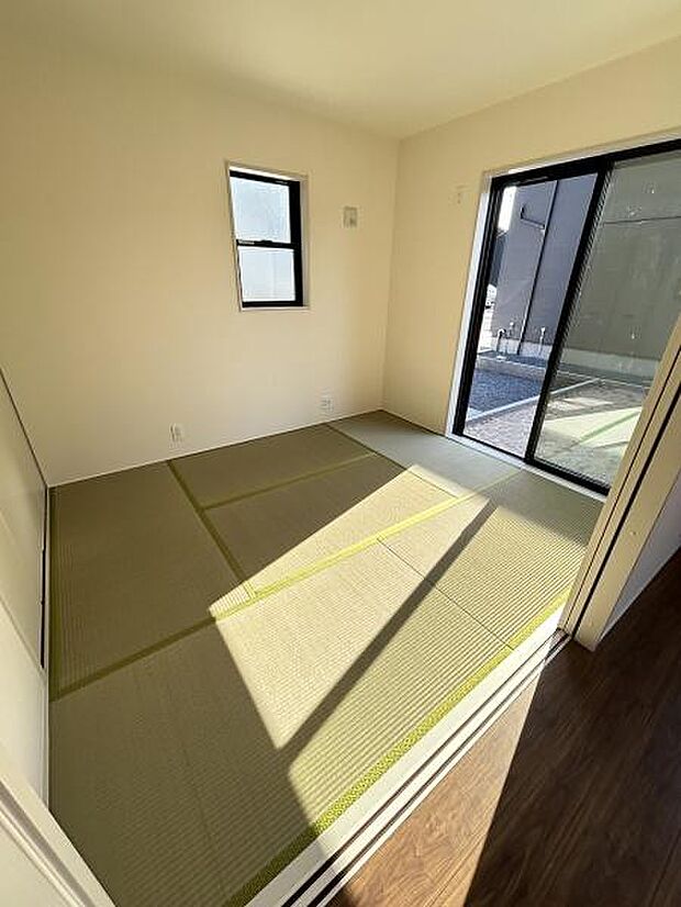 明るい日差しが差し込む和室です。畳の風合いが落ち着いた雰囲気を演出します。窓からは外の景色も楽しめます。シンプルな内装が空間の広がりを感じさせます。清潔感のある室内です。