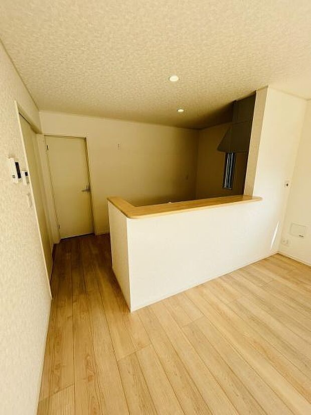 木目調の床とカウンターが調和したキッチンです。明るい内装が空間を広く感じさせます。カウンターキッチンのため調理や配膳がしやすい設計です。照明もバランスよく配置されています。