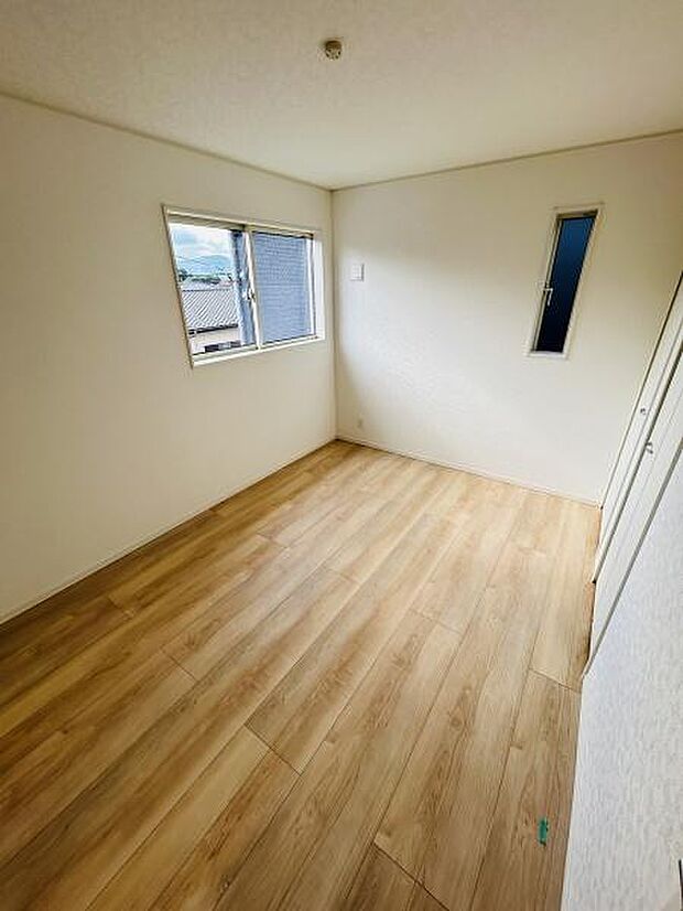 明るい色合いのフローリングが特徴の洋室です。2つの窓から光を取り入れることができます。シンプルな内装で空間を活かしやすいお部屋です。収納スペースも備わっています。清潔感のある印象です。