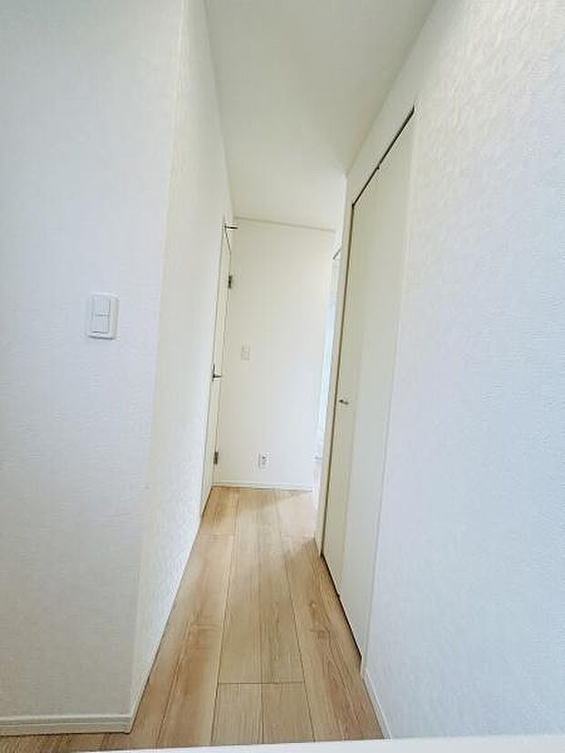 明るい色合いの壁と床が印象的な廊下です。すっきりとしたデザインが魅力的です。自然光が入りやすい空間で清潔感があります。直線的な動線が使いやすい印象です。収納スペースも確保されています。