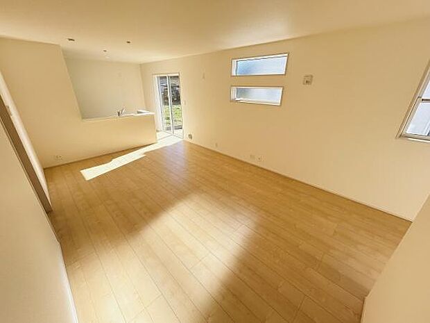 リビングは明るい陽射しが差し込み開放的な空間が広がります。ナチュラルな床材があたたかみを演出しています。窓が複数配置され通風や採光に配慮されています。キッチンとリビングがゆるやかにつながるつくりです。