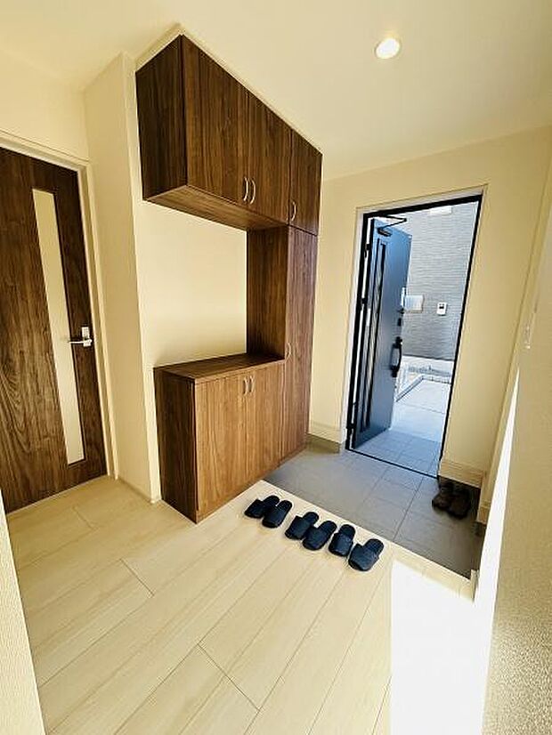 明るい光が差し込む玄関で開放感を感じられます。シンプルな木目調の収納が落ち着いた雰囲気を演出しています。使いやすい動線が印象的です。広めの土間スペースが設けられている点も特徴的です。