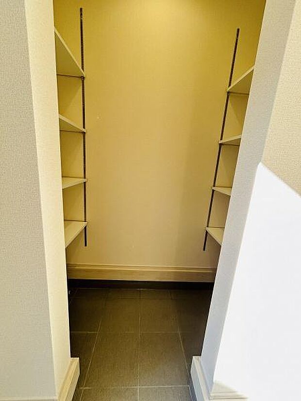 玄関には可動式の棚が両側に設置されており用途に合わせて配置を調整できます。足元はお手入れしやすいタイル仕様です。収納スペースがしっかり確保されているため整理整頓にも便利です。