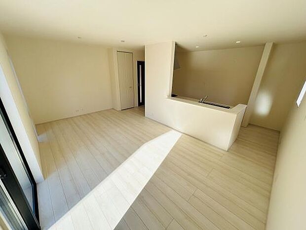 リビングは明るい日差しが差し込む空間となっております。広々とした造りでさまざまなインテリアを楽しめます。床は淡い色調で清潔感のある雰囲気です。オープンキッチンも特徴的なリビングです。