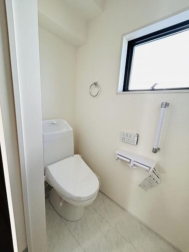 シンプルですっきりとしたトイレ空間です。明るい採光が魅力的で清潔感のある内装です。手すりやペーパーホルダーも備わっています。