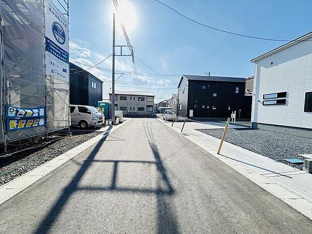 前面道路が広く車の出入りもスムーズに行えます。周囲は新しい建物が多く整った環境が感じられます。道路の舗装も新しくきれいな状態です。明るい雰囲気の現地写真です。