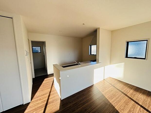 窓から差し込む光が明るい空間を演出します。キッチンとリビングがつながるレイアウトです。床材の色味が落ち着いた雰囲気を醸し出しています。直線的なデザインがすっきりとした印象です。