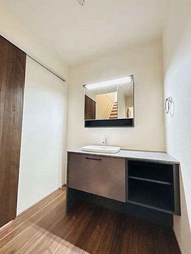 シンプルで洗練されたデザインの洗面台が印象的です。広々としたカウンターは日常の使い勝手にも配慮されています。鏡の上部に照明が設置されており明るさもしっかり確保されています。