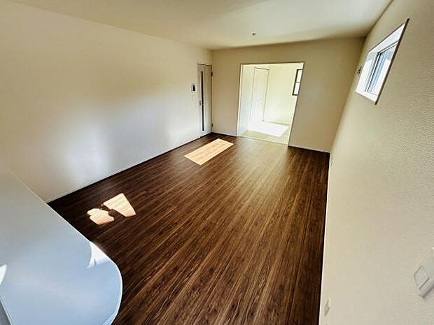 明るい光が差し込み開放感のあるリビングです。落ち着いた色合いのフローリングが空間を引き締めています。シンプルな内装で使いやすいレイアウトが可能です。小窓からの採光もございます。