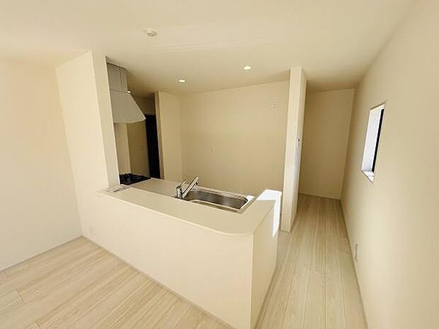 明るい色合いの床と壁で空間全体が開放的に感じられます。シンプルなデザインのキッチンで動線もスムーズです。カウンターキッチン仕様で使い勝手にも配慮されています。