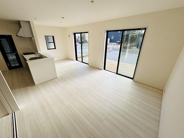 リビングには大きな窓があり開放感のある空間が広がっています。床材は明るい色合いで清潔感があります。キッチンも隣接しており使い勝手の良さが感じられます。