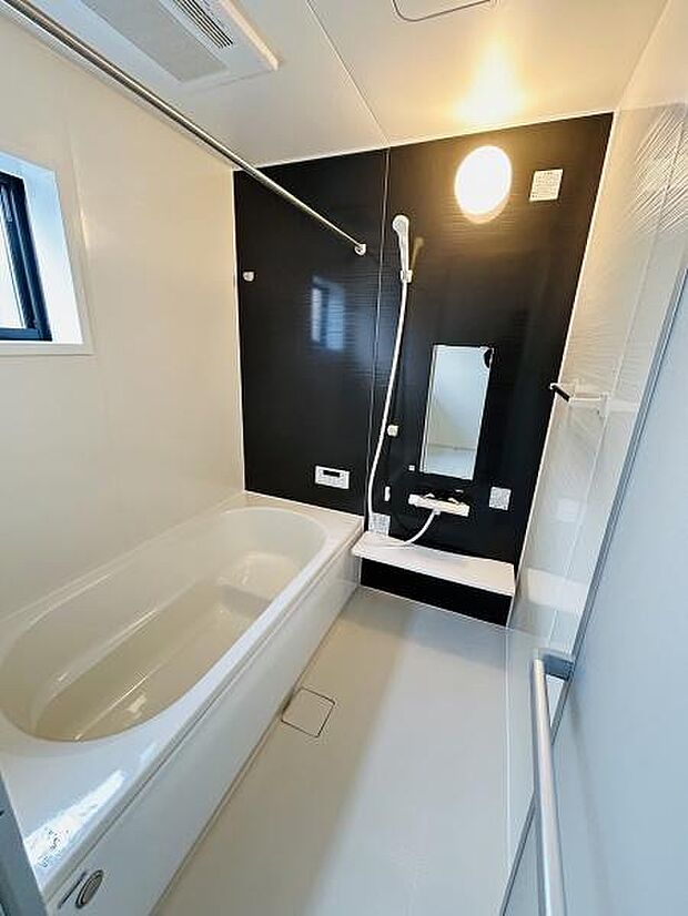 モノトーンのアクセントパネルが印象的なバスルームです。シンプルで使いやすいデザインになっています。大きめの鏡や小窓からの採光もポイントです。シャワーも手元で操作しやすい仕様です。