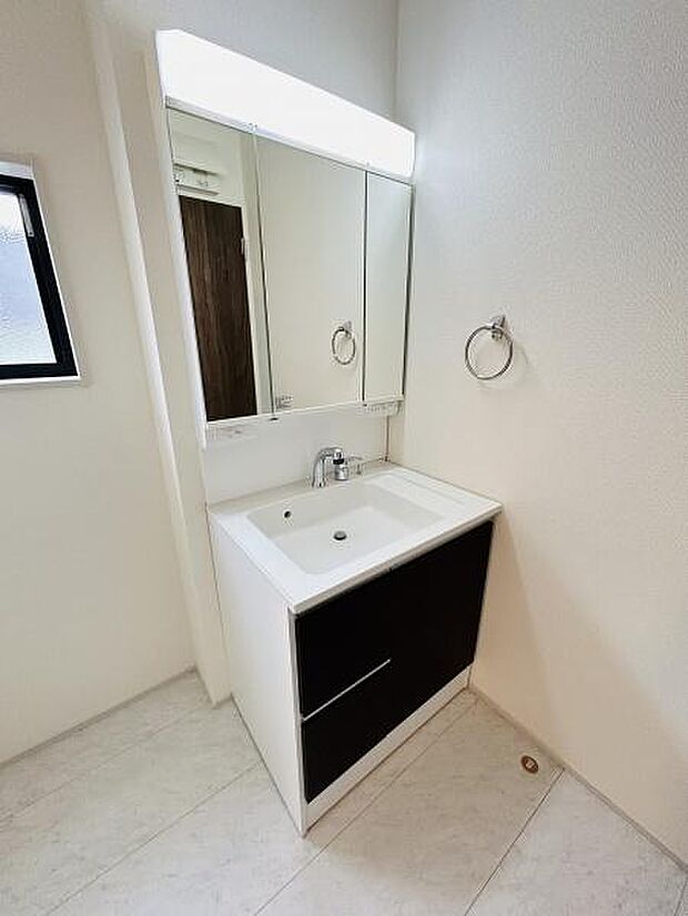 シンプルなデザインの洗面台が設置されています。清潔感のある白を基調とした空間です。鏡付きで毎日の身支度にも便利です。収納スペースも確保されています。