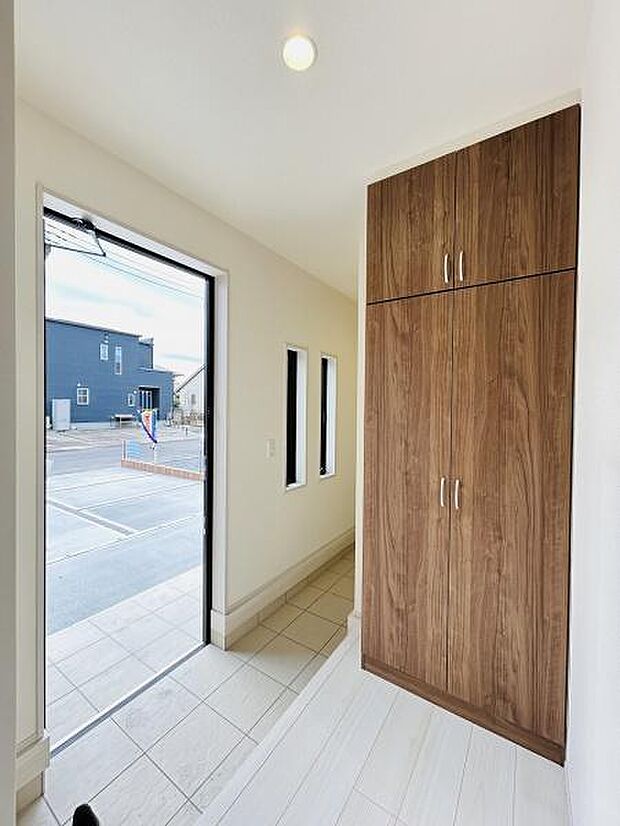 玄関は明るい雰囲気で清潔感があります。大型の収納が備わっており整理整頓がしやすいです。窓から外光が入り開放感を感じられます。全体的に落ち着いた色合いもポイントです。