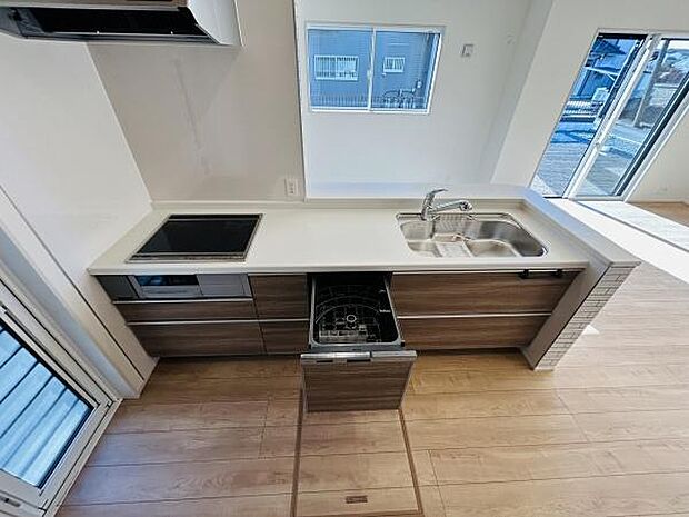 広々とした作業スペースを備えたキッチンです。シンクとコンロが使いやすく配置されています。収納も豊富で機能性が高い点が魅力です。食器洗い機も設置されています。明るい光が差し込む空間です。