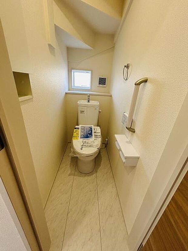窓付きで明るい雰囲気のトイレです。手すりが設置されており安全面にも配慮されています。収納やペーパーホルダーも備わっており使い勝手の良さが感じられます。落ち着いた色合いの内装が印象的です。