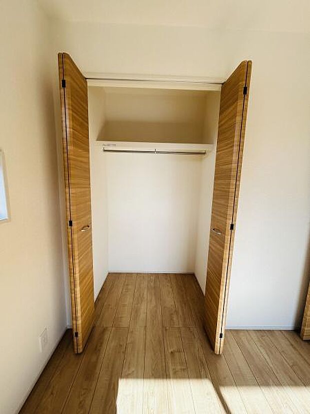 収納スペースがしっかり確保されています。木目調の扉が空間に温かみを与えます。内部にはハンガーパイプと棚が設置されておりすっきりと整理できます。シンプルなデザインで使い勝手の良い収納です。
