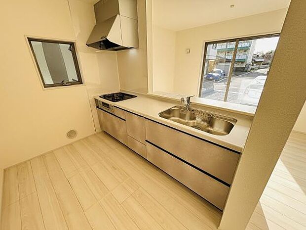 広々としたキッチンは収納スペースが豊富で使いやすい構造です。大きな窓から自然光が入り明るい印象となっています。シンプルなデザインで清潔感があります。床材との統一感もあり落ち着いた雰囲気です。
