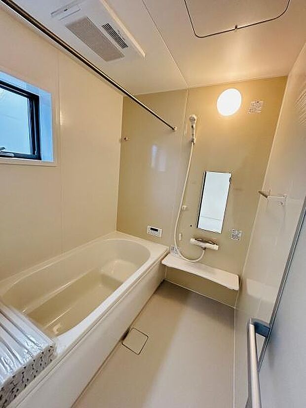 清潔感のあるバスルームです。明るい室内で快適な空間が広がっています。窓があり換気もしやすい設計です。手すりや鏡も備わっており使いやすさが考慮されています。