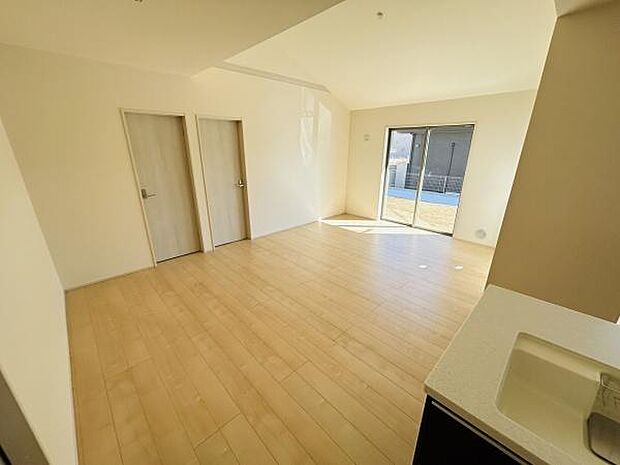 明るい光が差し込むリビングです。ナチュラルなフローリングが空間を広く感じさせます。掃き出し窓から庭へのアクセスも可能です。天井高があり開放感を楽しめます。扉が2つあり使い勝手の良い動線です。