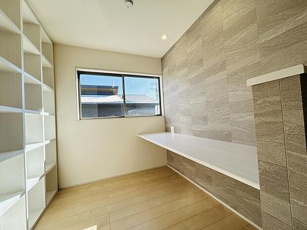 リビングには明るい窓がありナチュラルな木目調の床が広がっています。壁面には収納棚があり収納に便利です。スタイリッシュなカウンタースペースが配置されています。シンプルなデザインで使いやすい空間です。