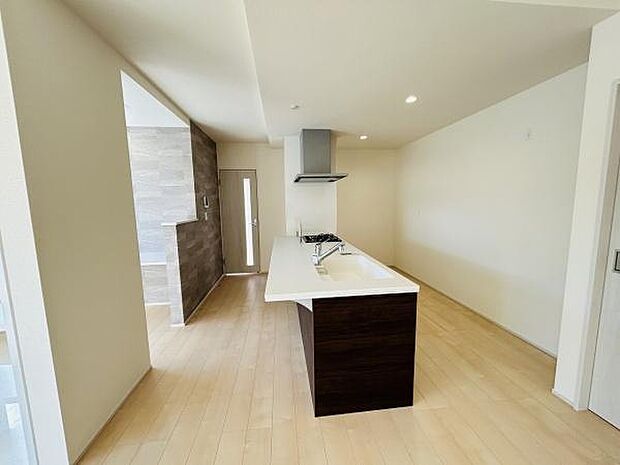 明るい色合いのフローリングと対面式のキッチンがすっきりとした空間を演出しています。天井のダウンライトが全体を均一に照らし開放感が感じられます。