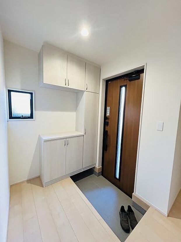 明るい玄関スペースが印象的です。収納も充実しておりすっきりとした空間を保てます。窓が設けられているため換気にも配慮されています。木目調のドアが温かみを感じさせます。