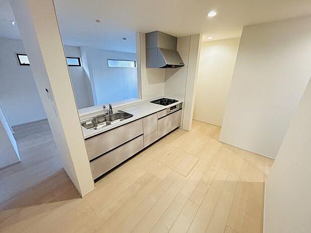 広々としたキッチンは収納スペースが豊富で使い勝手に優れています。シンプルなデザインが空間をすっきりと見せます。明るい色合いの床材が清潔感を感じさせます。コンロとシンクの配置が効率的です。