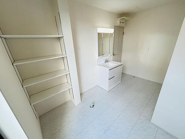 明るい空間に映える洗面台が設置されています。壁面には可動式の棚があり収納スペースが充実しています。清潔感のある床材が採用され使いやすさにも配慮されています。