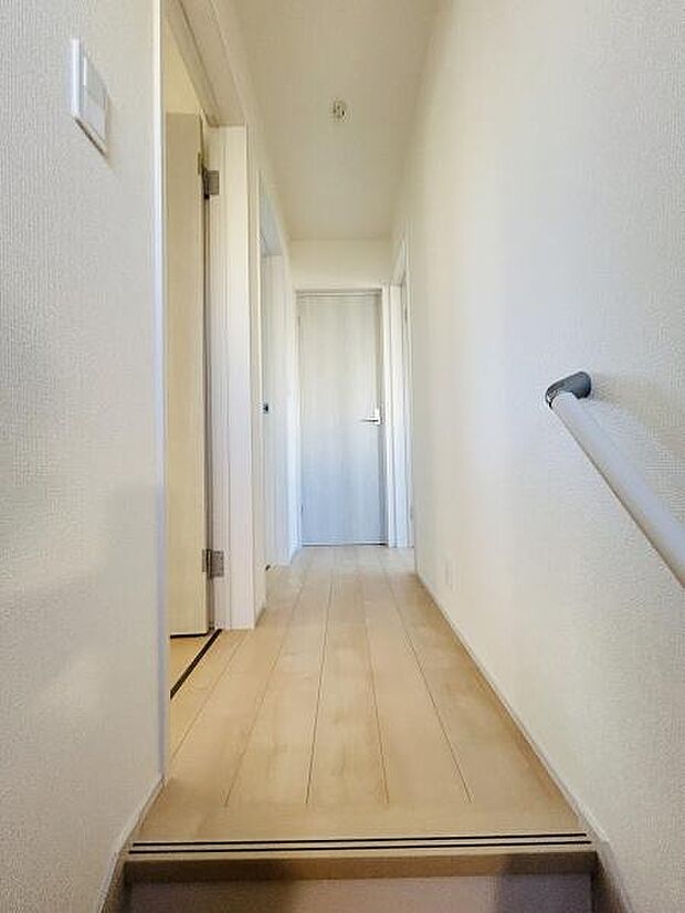 明るい色合いのフローリングが空間を爽やかに演出します。手すり付きで移動も安心です。奥行きのある廊下が広がりを感じさせます。掃除もしやすいシンプルなレイアウトです。室内の清潔感も伝わります。