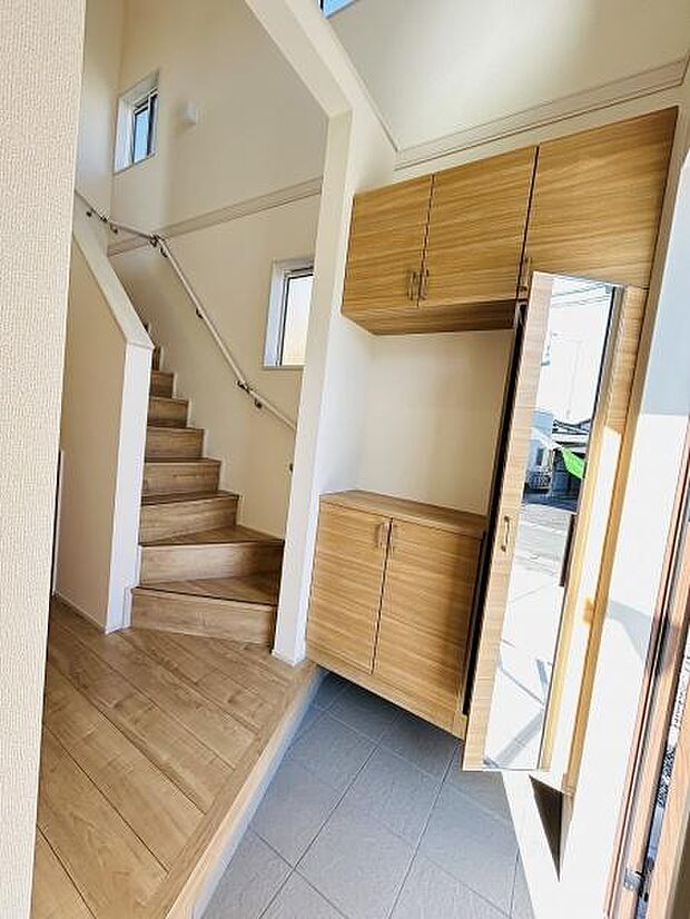 明るい玄関スペースが印象的です。シューズボックスには鏡が付いており外出前の身だしなみチェックに便利です。ナチュラルな木目調の収納で空間がすっきりしています。階段下のスペースも有効に活用されています。