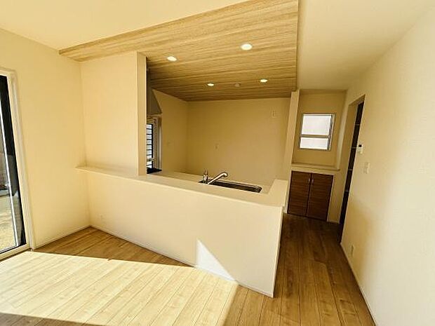 明るい日差しが差し込むリビングです。ナチュラルな木目調のフローリングが温かみを感じさせます。開放感のあるカウンターキッチンが空間を広く見せます。天井のウッドパネルがデザインのアクセントとなっています。