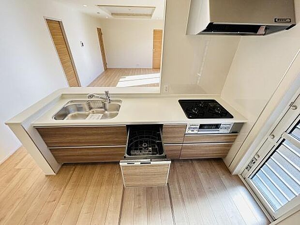 キッチンはすっきりとしたデザインでシンクとコンロが効率よく配置されています。引き出し式の収納もあり使い勝手に配慮されています。明るい空間が広がるレイアウトです。食器洗い機も設置されています。