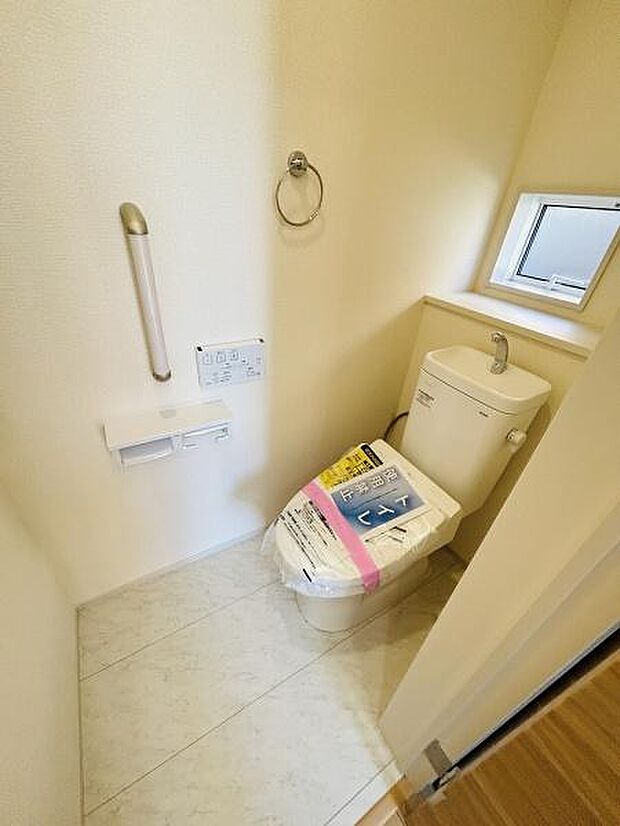 手すりが設置されており安心してご利用いただけます。窓が付いているため採光や換気も可能です。スペースがすっきりとまとめられています。床材はお手入れしやすい仕様です。清潔感のあるトイレ空間です。
