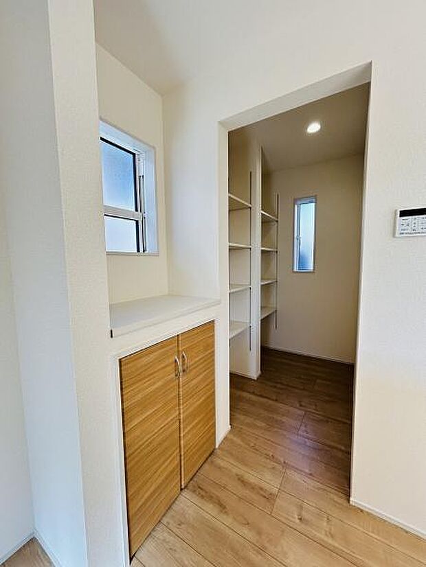 シンプルで統一感のある収納スペースです。可動棚が複数設置されており整理整頓しやすい設計です。使いやすい位置に収納が配置されており日常の動線も意識されています。木目調の扉が空間に温かみを加えています。