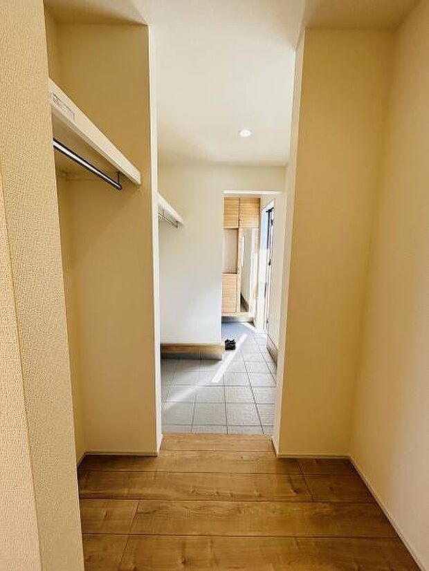ナチュラルな色合いの床材が空間を明るく演出しています。オープンなハンガーパイプが備え付けられており収納スペースとして活用できます。玄関からの動線も確保されていて使い勝手が良いです。