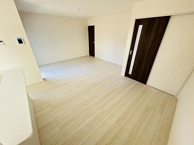 明るい色合いのフローリングが印象的なリビングです。シンプルで開放的な空間が広がっています。扉のダークカラーがアクセントになっています。余計なものがなくすっきりとした雰囲気です。