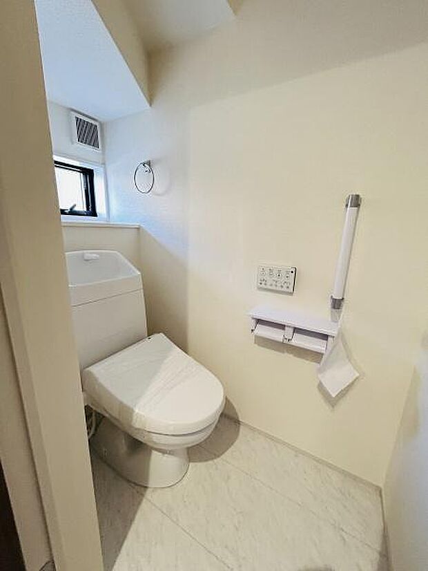 明るい色調の壁と床で清潔感のあるトイレ空間です。窓が設置されているため換気がしやすく快適に利用できます。壁には手すりも備え付けられているので使いやすさが感じられます。