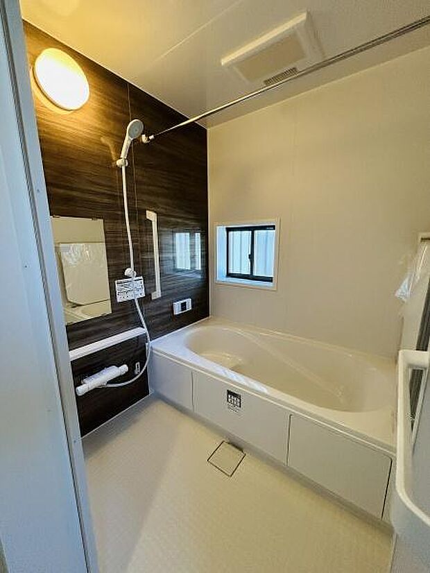 浴室の壁面は落ち着いたカラーでまとめられており明るい照明が室内全体をしっかり照らします。小窓が付いているため自然光や換気も期待できます。浴槽は足を伸ばせるサイズ感で使い勝手の良い空間です。
